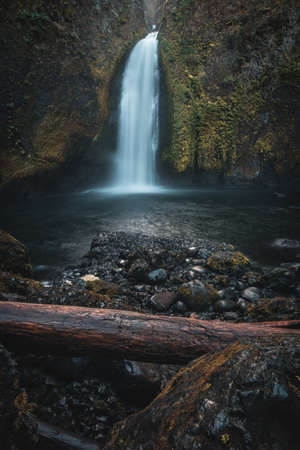 A vertical shot of a waterfall in the middle of a mountain streamの写真素材
