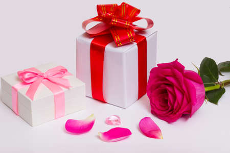 Gift boxes with bows and red ribbons. Glass heart and roses petals.の写真素材