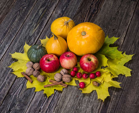 Pumpkins, apples and nuts with fall leaves on wooden background. Harvest. Farm.の写真素材