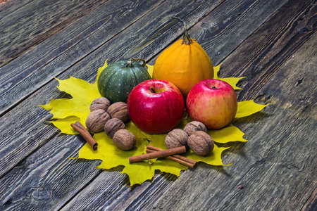 Pumpkins, apples and nuts with fall leaves on wooden backgroundの写真素材