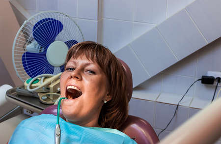 Girl patient during treatment at dentist office with saliva ejector.の写真素材