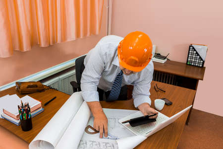 Engineer in helmet working with drawings. Check the drawing. Adjustment of the project.の写真素材