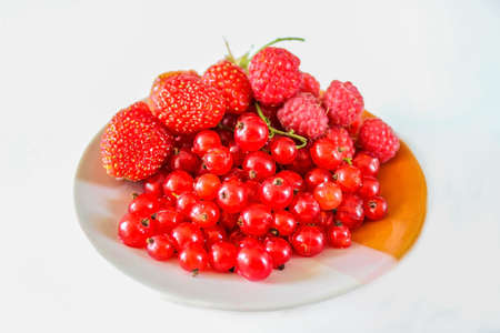 Berries red currants, strawberries and raspberries on a plate. Ripe fruit. Close-up.の写真素材