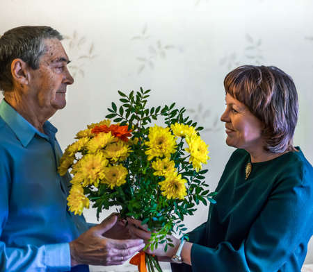 The girl gives flowers to an elderly man. Bouquet as a gift. Congratulation.の写真素材