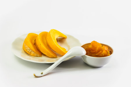 Sliced pumpkin on a plate and Pumpkin jam in saucer. Sweet dessert. Isolated on white background.