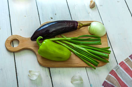 Eggplant, sweet pepper and green onion on a cutting board. Cooking. Ingredients for saute. Side view.の写真素材