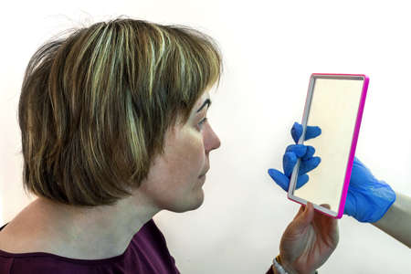 Eyebrow correction. Correcting the form. Drawing of a line of eyebrows in a beauty salon. A female patient looks in the mirror.の写真素材