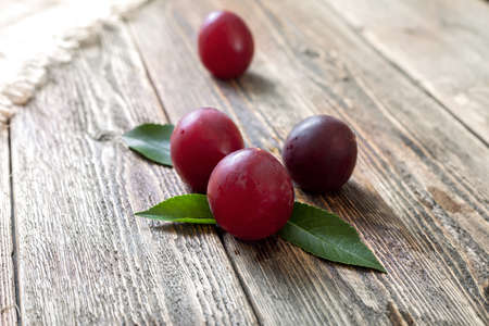 Ripe purple plums on a wooden table. Ripe fruit on a rough wooden background. Rustic cuisine.の写真素材