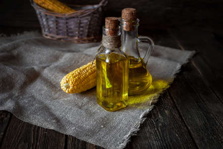 Ear of corn and bottles with corn oil on a wooden tableの写真素材