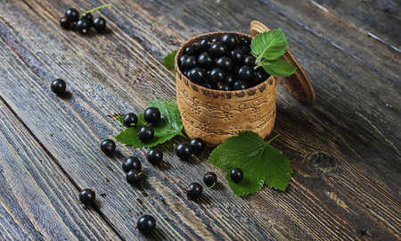 Black currant in a basket. Ripe forest berries. Wooden background.の写真素材