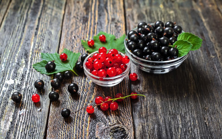 Black and red currants in a glass bowl. Rustic wooden table. Ripe forest berries on the table.