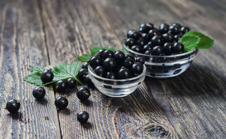 Black currants in a glass bowl. Rustic wooden table. Ripe forest berries on the table.の写真素材