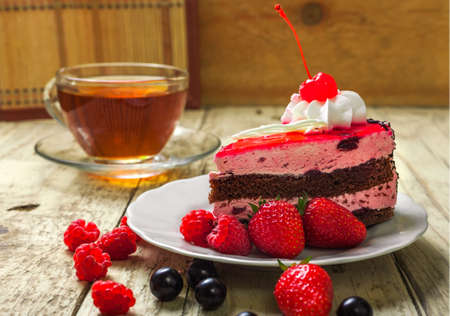 Chocolate cake with cream and berries. Biscuit with strawberries and currants. A piece of cake on a plate.の写真素材
