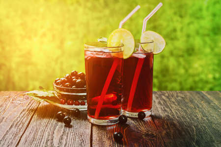 The juice of black currant in glass panes on the table is illuminated by bright sun rays.の写真素材