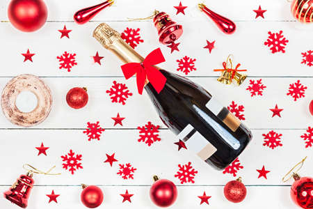A bottle of champagne lies on the table - around the bottle are snowflakes and fur-tree toys. Christmas spirit and Christmas mood.の写真素材