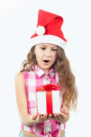 Beautiful little girl in a Santa hat with a gift - Christmas story. Isolated on white.の写真素材