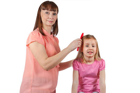 Mom combs her hair to her little daughter. Isolated on white background.の写真素材