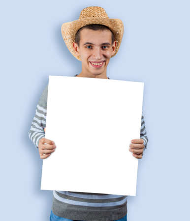 A young guy in a cowboy hat holds an blank placard. A template for farmer ads.の写真素材