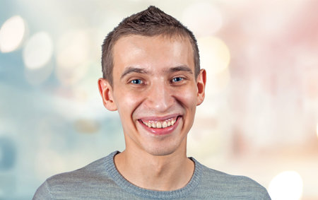 A young guy smiles carelessly at the camera on the background of city lights. Close-up.の写真素材