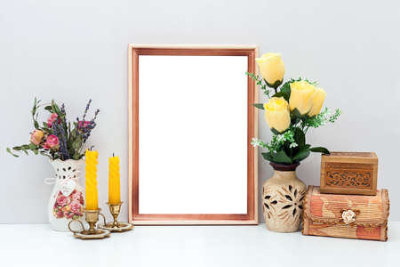 A4 wooden frame mockup with yellow flowers, candles and boxes. Portrait orientation.の写真素材