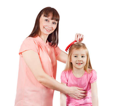Mom combs her daughter. Isolated on white background.の写真素材