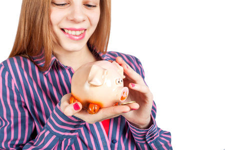 A beautiful girl is holding a piggy bank. Photo isolated on white background.の写真素材