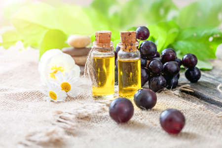 Essential oil of grape seeds on a wooden table - healing aromatic oilの写真素材