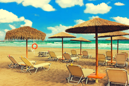 Straw umbrellas and chaise lounges on the southern tropical beach - sea view and blue sky