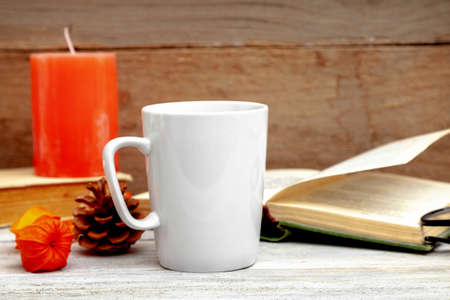 Mug mockup - design template, white cups on a wooden  with candle and booksの写真素材