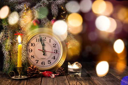 New Year - Candles, spruce branch and clock on dark backround.