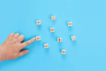 Conceptual image of creating a new business. A schematic representation of a trading network. Wooden cubes with images of people, dollars, shops, shopping carts.の写真素材