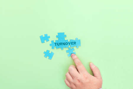 Businessman connecting puzzle pieces with the word Turnover. A conceptual image on the topic of business in sales.の写真素材