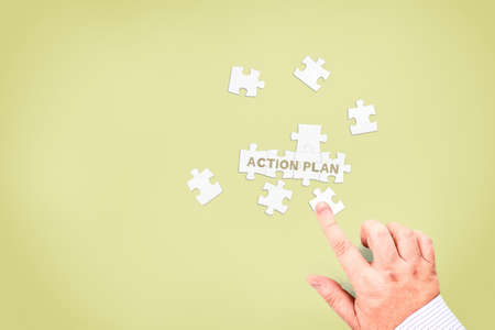 A businessman collects the words "Action plan" from puzzle pieces. Concept photo for action planning.の写真素材