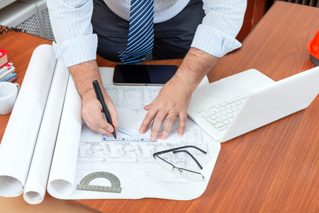 Workplace of a design engineer. Table with blueprints and computer.