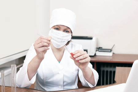 A female doctor in a mask works with blood tests. The study of blood tests for covid in the...