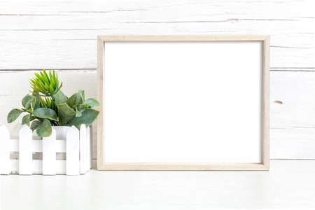 Mockup of a horizontal wooden frame on a light background. Frame 8x10 on the table with a flower.の写真素材
