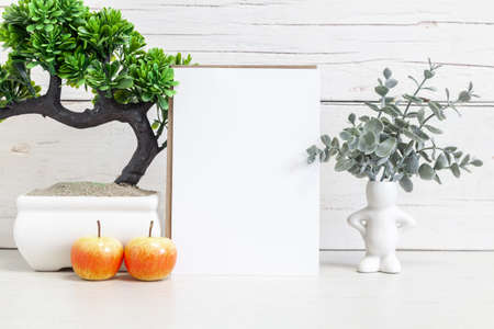 Party invitation mockup on a light background with flowers. Vertical white card 5x7 on the table against a light wall.の写真素材