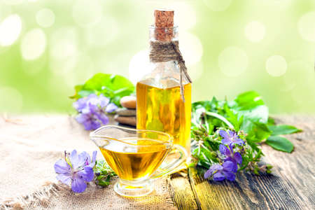 Linseed oil and blue flax flowers on the table against the backdrop of greenery. Flaxseed oil is an excellent source of nutrients and vitamins.の写真素材