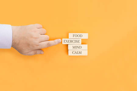 Basic health concepts - words written on wooden blocks. Food, exercise, mind, calm are concepts associated with a healthy lifestyle.の写真素材