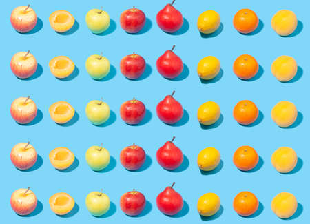 Ripe yellow apricots, apples, lemons and pears on light blue background - creative summer pattern - harvest conceptの写真素材