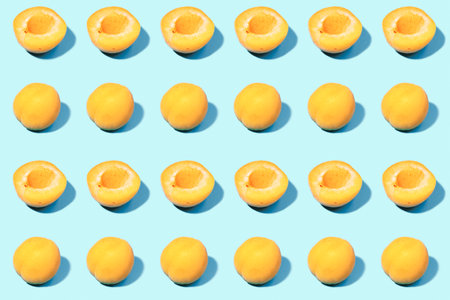 Summer pattern of ripe apricots on a blue background - fruit harvest concept - whole apricots and halvesの写真素材