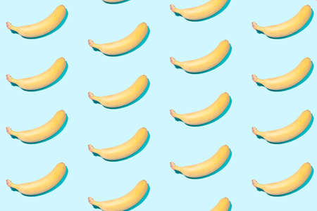 Creative summer background - yellow bananas on a light mint background in even rowsの写真素材