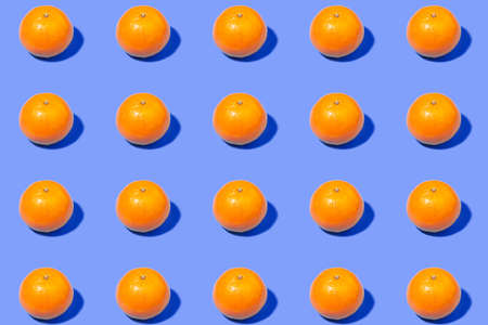 Bright orange tangerines on a purple background - a creative summer patternの写真素材