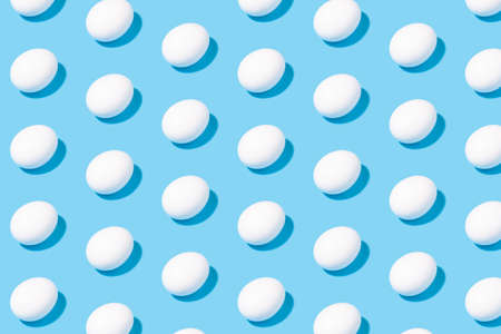 Creative minimalistic pattern - white chicken eggs on a blue background - geometric pattern for a creative backgroundの写真素材