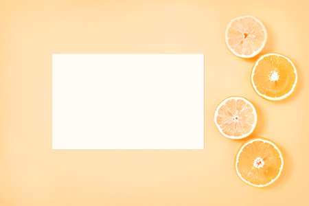 Gently yellow background with white paper sheet and citrus slices - creative summer mockupの写真素材