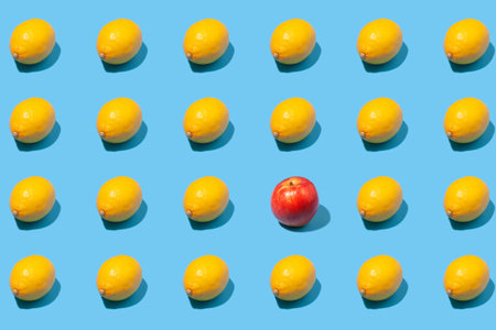 Creative pattern of yellow lemons and a red apple on a blue background. Minimal fruit concept.の写真素材