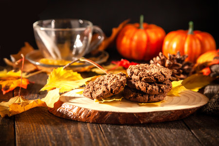 Autumn still life with oatmeal cookies, hot tea, pumpkins, candles and autumn yellow leaves. Autumn mood. Home warmth and coziness.の写真素材
