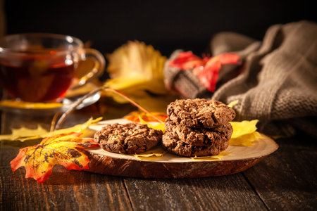 Autumn still life with oatmeal cookies, hot tea, pumpkins, candles and autumn yellow leaves. Autumn mood. Home warmth and coziness.の写真素材