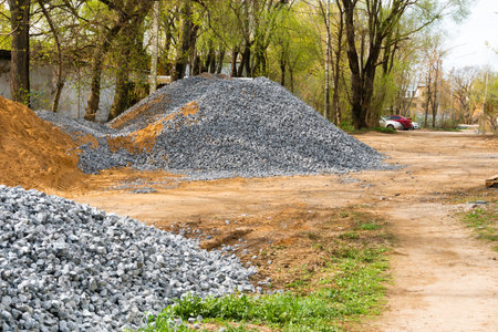 A pile of gravel prepared for road repair work. The site is being prepped for asphalt paving.の写真素材