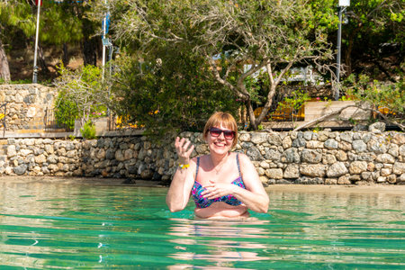 A young woman is joyfully enjoying a summer vacation in the clear waters of a tropical sea. A relaxing beach resort getaway.の写真素材